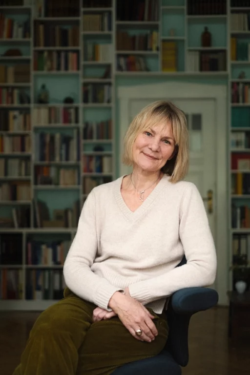 Gesa Kopf geneigt sitzend vor Bücherwand